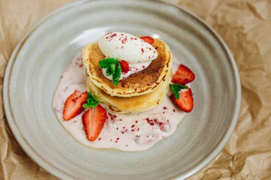 Masaya yeni bir tabak servis edilir. Dört çilek, büyük krep ve biraz sos var. Lezzetli, lezzetli ve tatlı görünüyor..