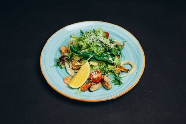 Yaratıcı şef tabağa yeni bir tabak koydu ve onu siyah masaya koydu. Ziyaretçiler tarafından yenmeye hazır. Biraz yeşil, domates, et, biber ve balık var. Lezzetli, harika ve lezzetli görünüyor. Ayrıca harika görünüyor..