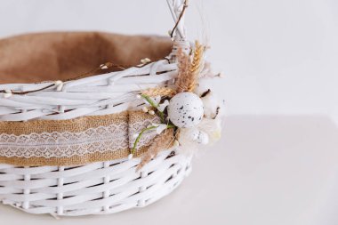 Beyaz arka planda dekoratif beyaz bir Doğu sepeti var. Çok güzel ve iyi hazırlanmış görünüyor. Doğu yemekleri için sepet kullanıyoruz. Sepetin üzerinde buğday ve güzel bir süs var..