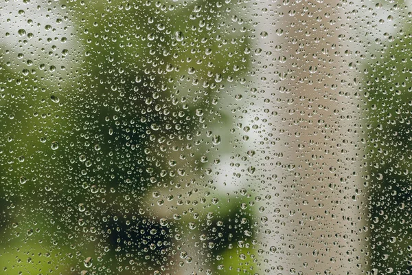 We can see a lot of drops of water on the window. It is rainy outdoors and the rain is quite relaxing. It is spring or autumn outside. The raindrops is quite wonderful.