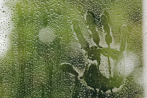 stock image There are a great view on the raindrops and hand-imprint on the background. The rain is quite relaxing. It is spring or autumn outside. The raindrops is quite wonderful and sad simultaneously.