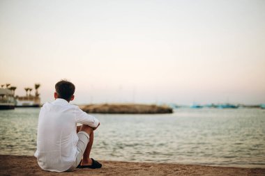 Bir adam kumsaldan güneşin doğuşunu izliyor.