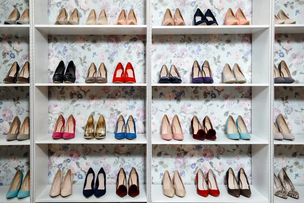 different colored shoes on a shelf in the store on a light floral background. organization of space in the store