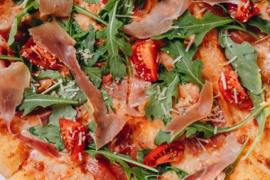 Tahta masadaki pizzacıda küçük bir pizza var. Bir sürü et, domates, biber, peynir görebiliyoruz. İnanılmaz lezzetli ve lezzetli görünüyor. Müşteriye servis edilir..