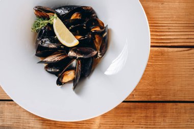 Beyaz kasede bir sürü istiridye var. Kasede bir dilim limon ve küçük bir yeşil var. Harika ve fantastik görünüyor, çünkü gerçek deniz ürünleri. Lezzetli ve lezzetli görünüyor..