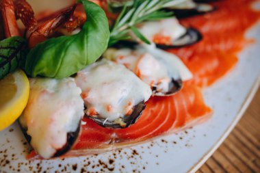 Restoranda yeni deniz ürünleri tabağı olan beyaz bir tabak var. Bir sürü deniz ürünü ve balık görebiliyoruz. Bir dilim limon, birkaç yaprak ve biber de var. Egzotik ve lezzetli görünüyor..