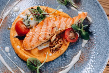 Dün menüde yer alan farklı bir yemeği görebiliyoruz. Mavi tabakta kızarmış balık, domates dilimleri, biraz yeşil ve oval ürün var. Egzotik ve ilginç görünüyor..