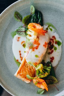 Krema soslu, karides ve kırmızı havyarla süslenmiş somon bifteği. Restoran servisi..