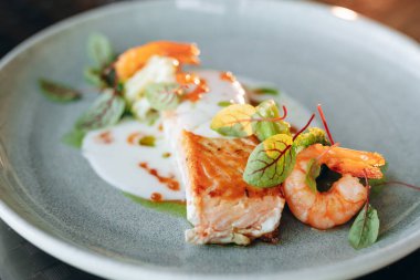 Krema soslu, karides ve kırmızı havyarla süslenmiş somon bifteği. Restoran servisi..