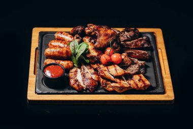 Tahtaya konmuş et. Kızarmış tavuk kanadı, domuz kaburgası, ızgara sebze, patates kızartması. Sos arkaplan resimli bira aperatifi, boşluk metnini kopyala