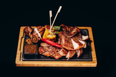 Sos soslu ızgara et, domuz eti ve tavukla ahşap bir tahtaya dizilmiş, restoran servisi..