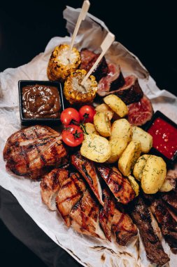 Sos soslu ızgara et, domuz eti ve tavukla ahşap bir tahtaya dizilmiş, restoran servisi..