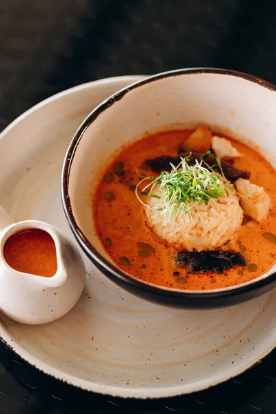 stock image Tom Yum Spicy Thai soup with shrimp in a black bowl on a dark background, top view.