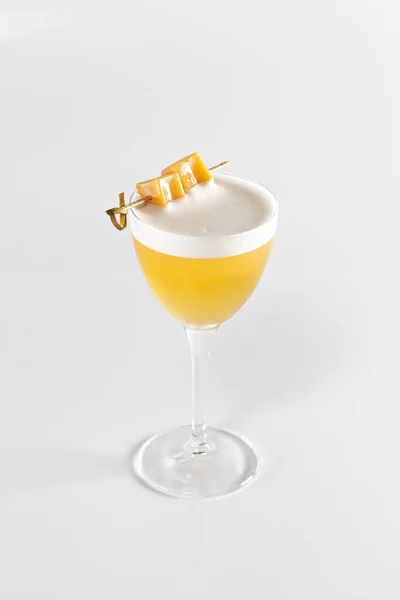 stock image Glass with yellow lemon cocktail on a white background. The drinks is decorated with caramel.