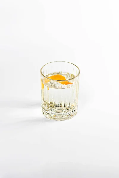 オレンジピールと氷で装飾された深いガラスにジンとトニックカクテル 白い隔離された背景で — ストック写真