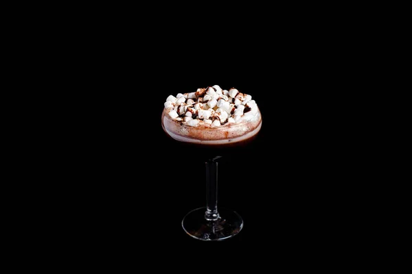 Chocolate shake with dripping sauce and marshmallows. On black background.
