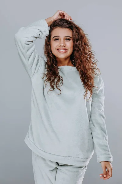 very sexy curly girl in a blue pajama night clothes on a gray background. home clothes concept. catalog photo. pajama skirt and pants