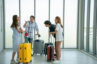 Yolculuktan önce havaalanı terminalinde eğlenirken Asyalı genç turist arkadaş grubu beşlik çakıyor.