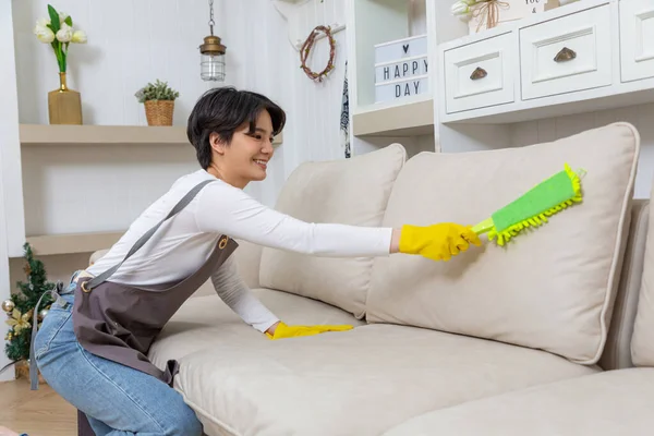 stock image Hygiene and cleanliness in the living room. A Cleaning lady with gloves wipes dust from furniture with a cloth.