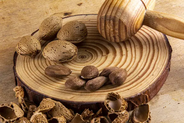 stock image Starting almonds on a wood, with a mace wood. Warm and rustic atmosphere.