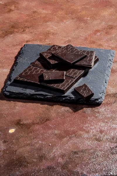 Black Chocolate Tablet Accompanied Chopped Slate Slab Photographed Studio Textured — Stock Photo, Image