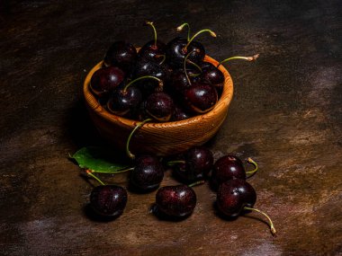 Ağaçtan yeni toplanmış kiraz kazmalarıyla el yapımı ahşap bir kase. Kırsal atmosfer. Yazar tarafından elle boyanmış arkaplanlar.