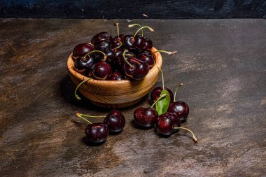 Ağaçtan yeni toplanmış kiraz kazmalarıyla el yapımı ahşap bir kase. Kırsal atmosfer. Yazar tarafından elle boyanmış arkaplanlar.
