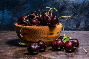 Ağaçtan yeni toplanmış kiraz kazmalarıyla el yapımı ahşap bir kase. Kırsal atmosfer. Yazar tarafından elle boyanmış arkaplanlar.