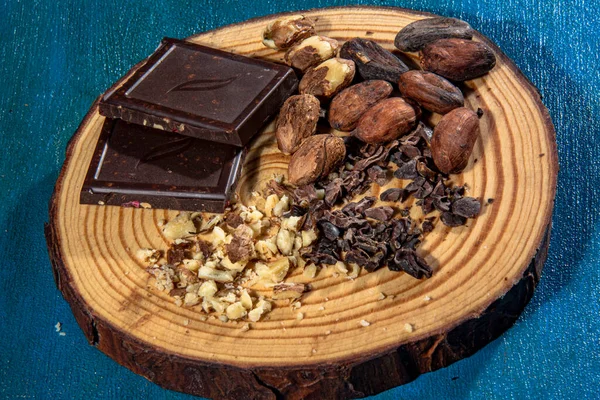 Pieces Dark Chocolate Hazelnuts Placed Slice Trunk Textured Blue Background — Stock Photo, Image