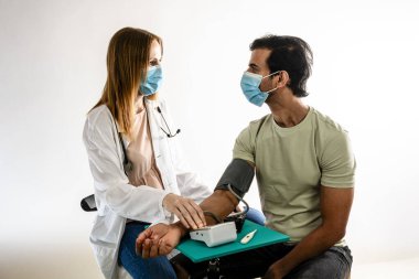 Hintli bir Asyalı hastaya kan basıncını ölçen kadın doktor. Beyaz arkaplan.