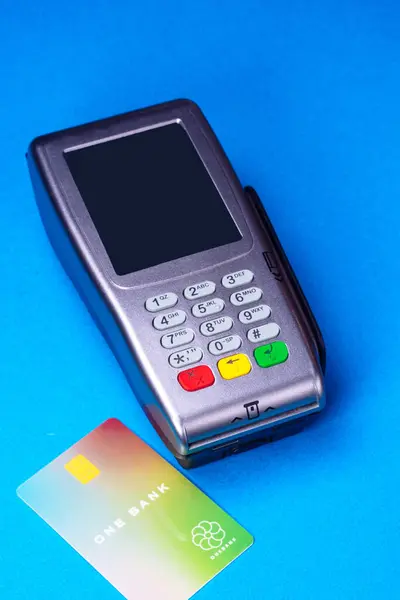 Credit card reader with card on the side, studio shot on medium blue background. Fake card, not operative.