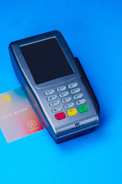 Credit card reader with card on the side, studio shot on medium blue background. Fake card, not operative.
