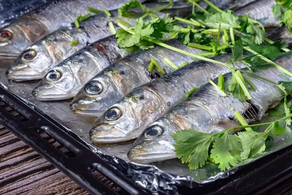 A tray of fish with parsley on top. The fish are cut in half and arranged on a tray, close up.