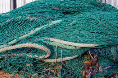 İp ve zincirlerle birbirine dolanmış yeşil balık ağlarının yakın çekimleri ayrıntılı doku ve desenleri sergiliyor. Ticari balıkçılık için gerekli.
