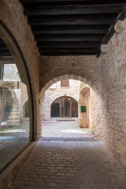 Gironas 'ın eski kasabasındaki bir avluya giden taştan bir kemer yolu, tarihi mimari ve kaldırım taşı yollarını aydınlatıyor..