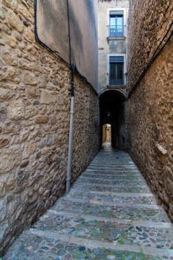 Ortaçağ mimarisini yansıtan antik taş duvarlar ve tarihi binalarla çevrili Girona kasabasındaki dar kaldırım taşı sokak..