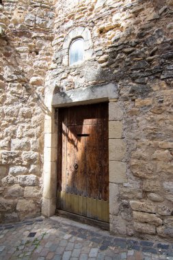 Ortaçağ mimarisi ve cazibesini sergileyen Girona 'nın tarihi Yahudi mahallesindeki taştan bir duvarın içindeki ahşap kapı..