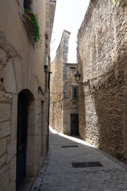 Gironas 'ın eski bir kasabasında dar bir taş sokak, antik kaldırım taşları ve tarihi binalar sergileniyor, ortaçağ kentsel tasarımını temsil ediyor..