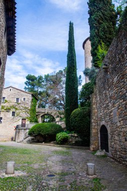 Girona 'nın tarihi bölgesinde eski taş binalar ve canlı yeşilliklerin yer aldığı manzaralı taş avlu..