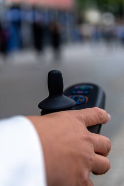 Güçlü bir tekerlekli sandalyenin kontrolünü eline alan, şehir planına karşı koyan, kentsel hareketlilikteki yardımcı cihazların rolünü vurgulayan bir kişinin yakın çekimi.