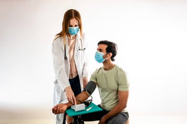 Hintli bir Asyalı hastaya kan basıncını ölçen kadın doktor. Beyaz arkaplan.