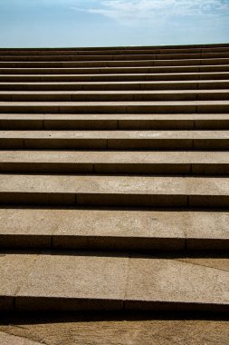 Açık havada taş merdivenlerin yakın görüntüsü, gösterişli simetri, dokular ve yukarıda parlak bir gökyüzü..