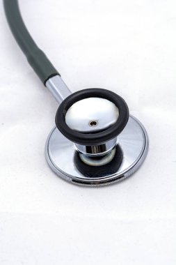 Bir steteskopun dikey görüntüsü. Metalik göğüs parçası. Siyah kauçuk kenar ve yeşil borular..