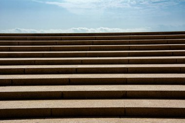 Mimari basitlik ve geometrik dengeyi vurgulayan, dingin mavi gökyüzünün altındaki simetrik taş merdiven.