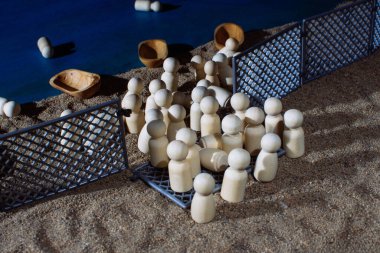 Wooden figurines with small boats trapped behind fences on sand, symbolizing migration, borders, and struggles for freedom. clipart