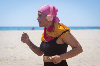 Close-up of a focused middle-aged woman with cancer jogging on the beach, showcasing resilience clipart