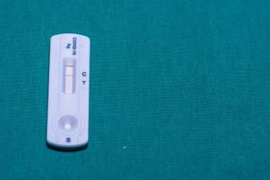Bir COVID-19 antijen hızlı test kasetinin yakın çekiminde tek bir kontrol hattı görüntülenir, negatif bir sonuç gösterir, bir deniz mavisi arkaplanına yerleştirilir..