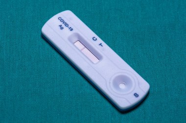 Bir COVID-19 antijen hızlı test kitinin yakın çekimi iki çizgi gösteriyor, olumlu bir sonuç, bir gök mavisi arkaplan karşı ayarlanır.