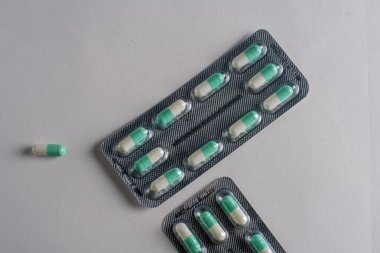 Yeşil ve beyaz kapsüllerle dolu su toplayıcı paketler, tek bir kapsül düz bir yüzeye yerleştirilmiş, yakın çekim görüntüsü.