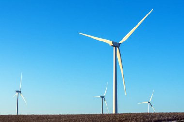 İspanya 'nın Katalonya kentindeki kırsal bir tepede güneşli bir günde açık mavi gökyüzünün altında yenilenebilir enerji üreten birçok rüzgar türbini bulunuyor..